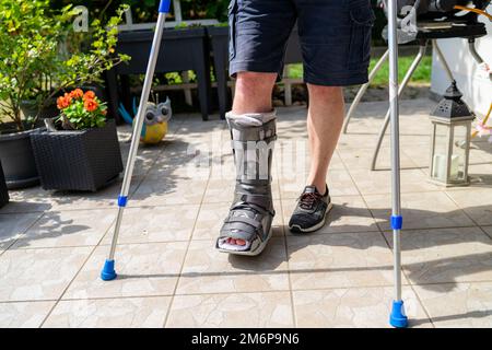 Beinbruch mit Orthese und Krücken nach Unfall in Bayern. Stockfoto