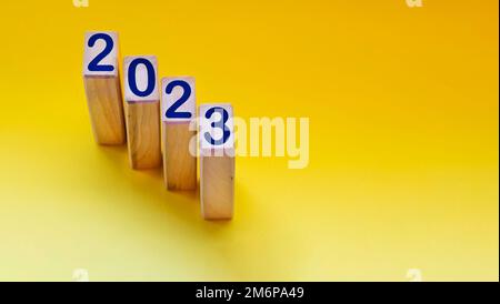 Blöcke mit der Zahl 2023 auf gelbem Hintergrund. Geschäftsziele für das nächste Jahr. Neujahrskonzept 2023. Stockfoto