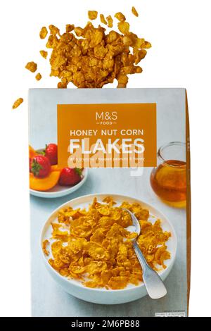 Karton mit Honignuss-Cornflakes mit knusprigen gehackten Erdnüssen und Honiggetreide von M&S, geöffnet mit verschüttetem Inhalt auf weißem Hintergrund Stockfoto