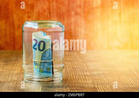 Geld rollt in einem Glas auf einem Holzhintergrund Stockfoto