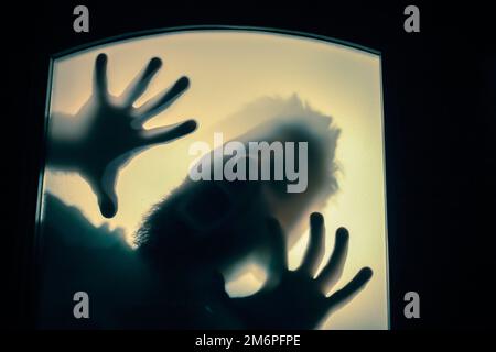 Gruseliges Bild von Händen hinter Glas, Horror-Geisterfrau hinter der Tür, Halloween-Konzept Stockfoto