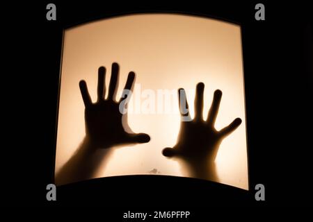 Gruseliges Bild von Händen hinter Glas, Horror-Geisterfrau hinter der Tür, Halloween-Konzept Stockfoto