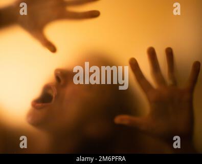 Gruseliges Bild von Händen hinter Glas, Horror-Geisterfrau hinter der Tür, Halloween-Konzept Stockfoto