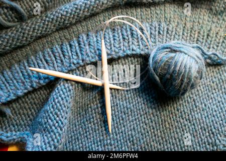 Kreisförmige Stricknadeln auf dem Hintergrund der blauen klobigen Wollkugel aus Wolle stricken handgemachte Pullover Craft Wales UK KATHY DEWITT Stockfoto
