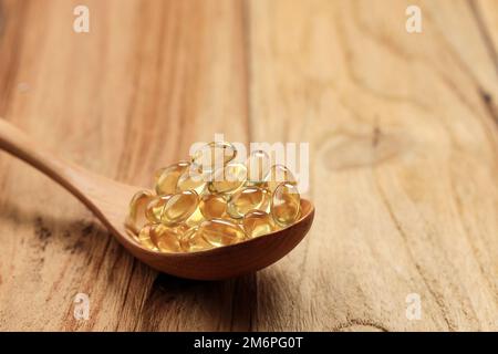Fischölkapseln auf Holzlöffel. Bereich für Text kopieren Stockfoto