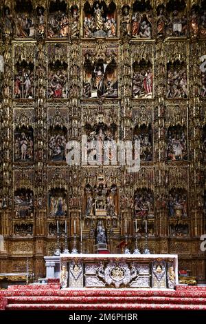 Sevilla, Spanien - 7. Dezember 2021: Ein schöner antiker Hauptaltar in der Kathedrale von Sevilla, dekoriert mit kleinen Jesus und Heiligen Holzstatuen. Stockfoto