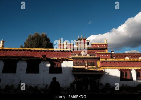 Tibetische Architektur. Traditionelles tibetisches Haus im Sonnenlicht und blauem Himmel mit Wolkenhintergrund. Haus mit Ornamenten in der Provinz Sichuan, China. Stockfoto