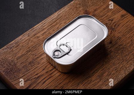 Rechteckige Dose aus Zinn oder Aluminium mit einem Schlüssel auf dunklem Betonhintergrund Stockfoto