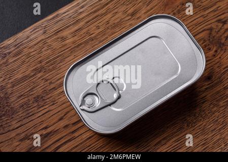 Rechteckige Dose aus Zinn oder Aluminium mit einem Schlüssel auf dunklem Betonhintergrund Stockfoto
