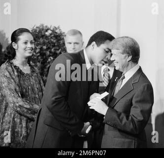 Präsident Jimmy Carter begrüßt Muhammad Ali bei einem Weißen Haus-Dinner, 1977. Links ist die Frau von Ali, Veronica Porché Ali. Stockfoto