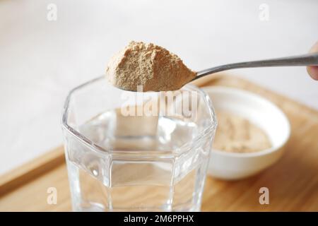 Brauereihefen-Flocken in einem Glas Wasser mischen Stockfoto