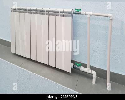 Weiße, moderne Aluminium-Heizkörperbatterie für Warmwasserheizung, auf dem Hintergrund einer Wand im Wohnungsinneren oder außerhalb Stockfoto