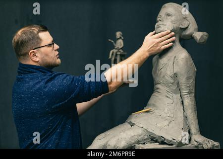 Mann Bildhauer schafft Skulptur Büste Ton menschliche Frau Skulptur. Werkstatt für die Erstellung von Statuen Stockfoto