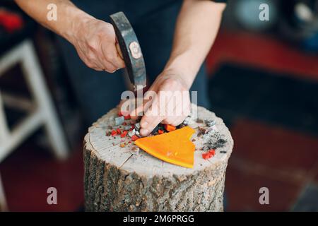 Handwerker, die in der Werkstatt mit einem Hammer Glasscherben für Mosaikkunstwerke zerschneiden Stockfoto