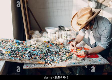 Mann Mosaiken Meister wählt ausgewählte Smaltglasstücke für Mosaik-Panel. Männlicher Mosaikist bei der Arbeit. Stockfoto