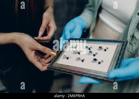 Eine junge Frau, die im Schönheitssalon Ohrpiercing macht. Stockfoto