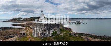 Blick auf die Landzunge Mumbles mit dem historischen Leuchtturm und den Piers in Swansea Bay Stockfoto