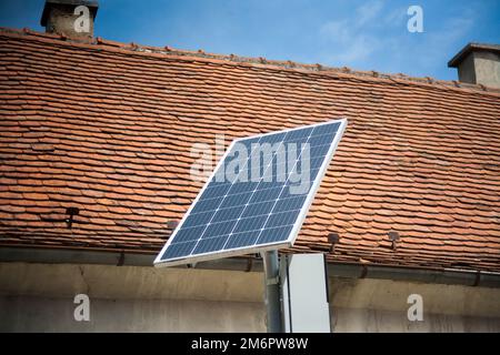 Installierte Solarpaneele auf der Straße. Rotes Dach dahinter. Stockfoto