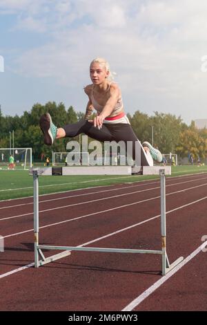 Eine junge Sportlerin, die Hürden läuft Stockfoto