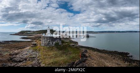 Blick auf die Landzunge Mumbles mit dem historischen Leuchtturm und den Piers in Swansea Bay Stockfoto