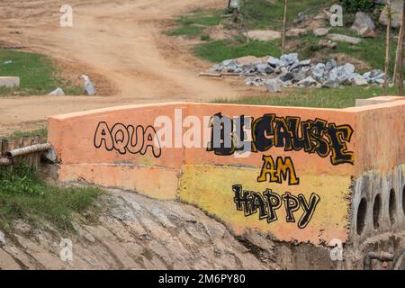 Bunte Schrift, die lautet „Because I am happy“, schmückt eine Betonentwässerungsstruktur im Freien. Stockfoto
