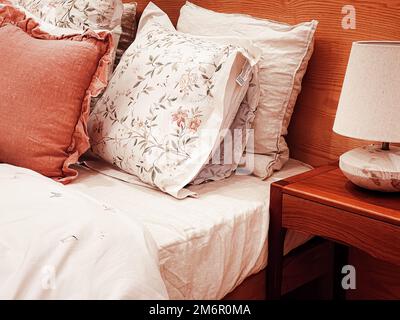 Bettwäsche im Landhausstil im Vintage-Stil mit Blumenmuster auf Holzbett im Schlafzimmer, Inneneinrichtung Stockfoto