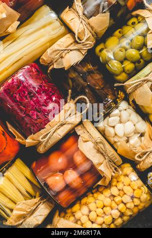 Geschlossene Einmachgläser mit verschiedenen Gemüsesorten auf Steintisch Stockfoto