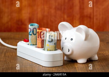 Weißes Sparschwein und elektrisches Verlängerungskabel mit Euro-Währung Stockfoto