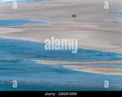 Malerischer Sandstrand und blaues Meerwasser. Ein paar Leute in der Ferne an einem wunderschönen Strand. Der berühmte irische Strand von Inchydoney, eine minimalistische La Stockfoto