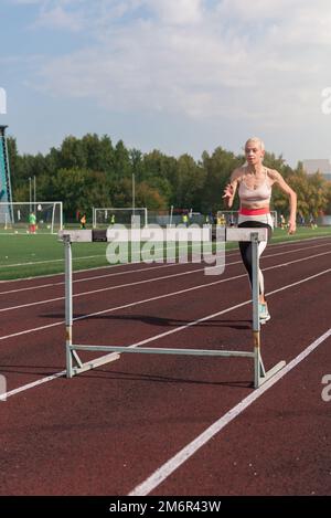 Eine junge Sportlerin, die Hürden läuft Stockfoto