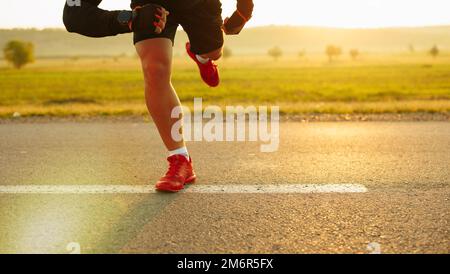 Detaillierte Ansicht eines Sprinterers, der sich auf den Start vorbereitet. Selektiver Fokus. Schönes Feld und helle Sonne im Hintergrund. Stockfoto