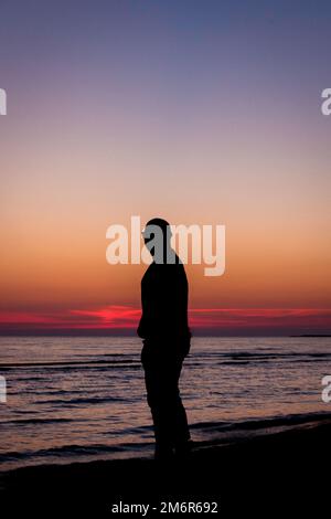 Silhouette eines Mannes am Strand bei Sonnenuntergang Stockfoto