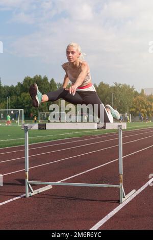 Eine junge Sportlerin, die Hürden läuft Stockfoto