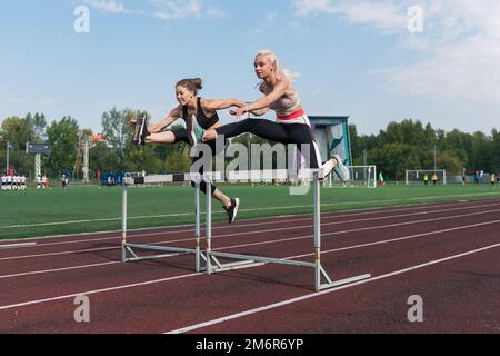 Zwei Sportlerinnen, die Hürden laufen Stockfoto