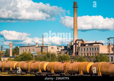 Die Eisenbahn führt durch das Industriegebiet mit einem großen Werk Stockfoto