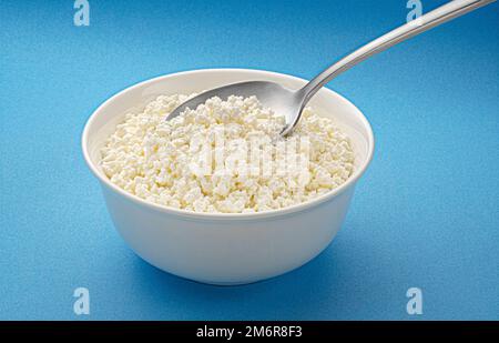 Schüssel Quark mit Löffel auf blauem Hintergrund Stockfoto