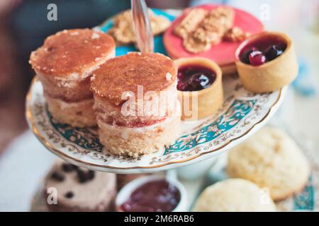 Nachmittagstee mit Keramikplatten mit Scones, Cupcakes und Mini Marmeladentörtchen auf der Geburtstagsparty eines Kindes Stockfoto