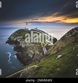 Ein Luftbild des South Stack Lighthouse auf einer Klippe unter den dramatischen Wolken und dem goldenen Sonnenuntergang Stockfoto