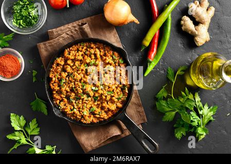 Keema Curry in Pfanne auf schwarzem Steinhintergrund. Indisches und pakistanisches Gericht. Draufsicht, flach liegend Stockfoto