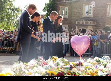 Datei Foto vom 10/09/22 des damaligen Prinzen und Prinzessinnen von Wales (rechts) und des Herzogs und der Herzogin von Sussex, der die Botschaften und Blumenwürdigungen ansieht, die Mitglieder der Öffentlichkeit in Windsor Castle in Berkshire nach dem Tod von Königin Elizabeth II. Hinterlassen haben Der Herzog von Sussex hat angeblich behauptet, er sei von seinem Bruder wegen seiner Ehe mit Meghan Markle angegriffen worden. Ausgabedatum: Donnerstag, 5. Januar 2023. Stockfoto