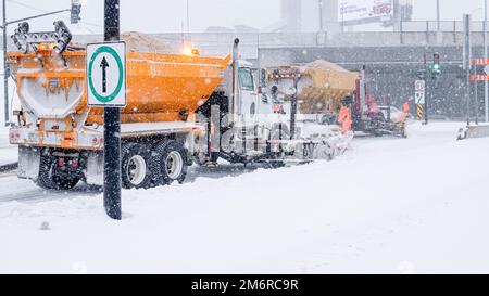 Schneepflug-Truck in der Stadt. Winterfahrzeug. Schneeräumung auf der Straße. Schneeräumung auf der Straße. LKW, der Salz einbringt. Zwei Schneepflüge, die Schnee entfernen. Stockfoto