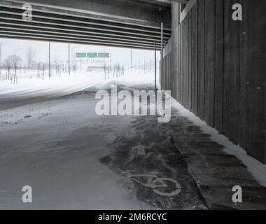 Radweg unter dem Schnee. Nahaufnahme von Schnee auf der Straße. Unmöglich, ein Fahrrad zu nehmen. Schneesturm. Die Straße war mitten im Sturm mit Schnee bedeckt. Stockfoto