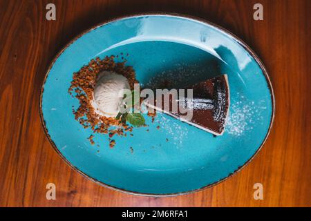 Schokoladenkuchen mit Keksen und einer Kugel Vanilleeis mit Blick auf den Tisch. Stockfoto