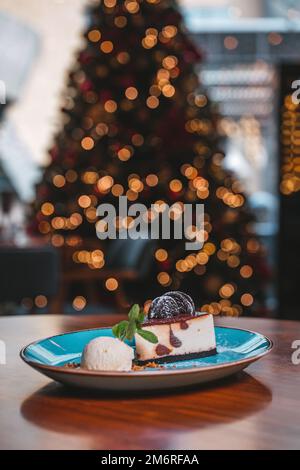 Ein wunderbares Stück Käsekuchen mit Vanilleeis auf einem blauen Teller in einem Café. Stockfoto