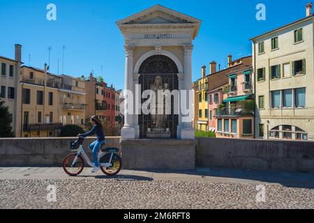 Madonna Schrein Italien, Blick auf eine junge Frau, die an einer Madonna und einem Kind vorbeifährt, die in einer Nische auf der Ponte Molino (römische Brücke) in Padua, Italien, sitzt Stockfoto