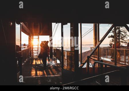 Vancouver, Kanada - Dezember 16,2022: Menschen auf dem Gipfel des Grouse Mountain Ski Resort im Skyride Gebäude bei Sonnenuntergang Stockfoto