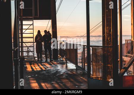 Vancouver, Kanada - Dezember 16,2022: Eine glückliche Familie auf dem Gipfel des Skigebiets Grouse Mountain im Skyride-Gebäude bei Sonnenuntergang Stockfoto