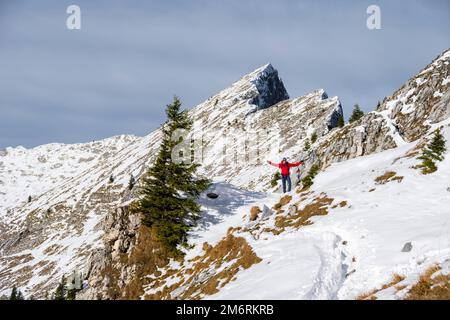 Glücklicher Wanderer, der seine Arme in der Luft streckt, Wanderweg im Winter, Pfad zur Ammergauer Hochplatte, Ammergau Alpen, Bayern, Deutschland Stockfoto