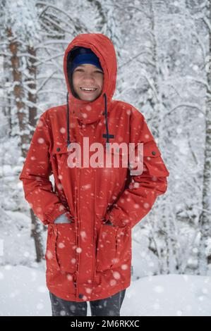 Ein Junge, der in einem verschneiten Winterwald spaziert Stockfoto