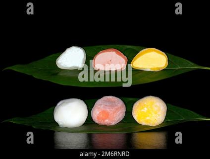 Japanisches Mochi-Eis gefüllt mit Yuzu, Mango und Erdbeere, Lebensmittelfotografie mit schwarzem Hintergrund Stockfoto